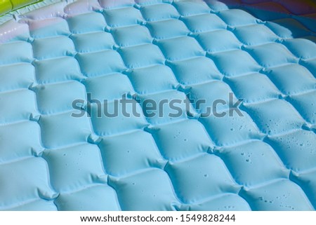 Bright blue inflatable paddling pool surface with water ripples. Summer picture of swimming pool. Background or backdrop