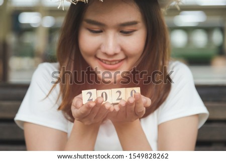 Close up shot beautiful Asian woman with a smile holding wooden blocks number 2020, Happy new year concept.