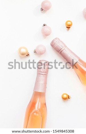 Christmas or New Year composition with bottles of rose champagne and golden shiny sparkle star confetti isolated on white background, top view. Celebration flat lay. Party creative concept