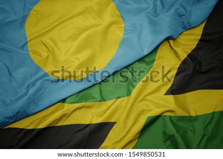 waving colorful flag of jamaica and national flag of Palau . macro