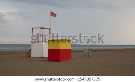 red and yellow flag warning on the beach with a lookout
