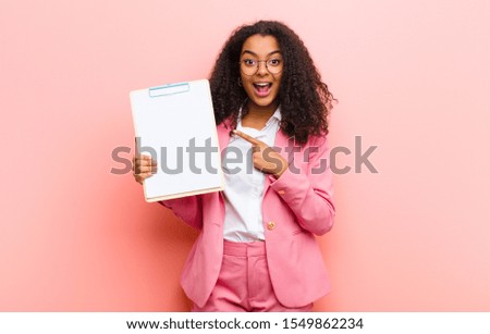 young black pretty woman with a paper sheet against pink wall background