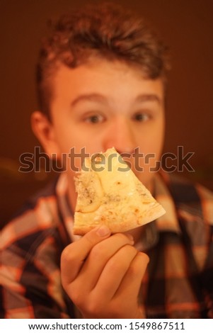 teen boy eats pizza and enjoys it, closeup enjoying and savoring.