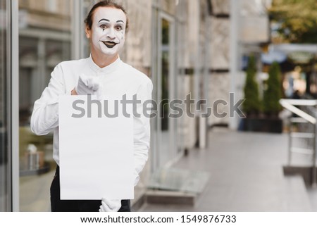 Your text here. Actor mime holding empty white letter. Colorful portrait with gray background. April fools day