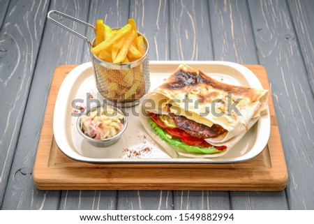 Pita with roasted chicken and vegetables, served with a delicious sauce. On a wooden table. Tasty food