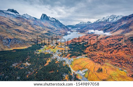 View from flying drone. Gloomy autumn view of Sils lake. Dramatic morning scene of Swiss Alps. Aerial outdoor scene of Maloya village, Switzerland, Europe. Beauty of nature concept background.