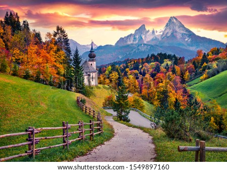 Iconic picture of Bavaria with Maria Gern church with Hochkalter peak on background. Fantastic autumn sunrise in Alps. Superb evening landscape of Germany countryside. Traveling concept background. Royalty-Free Stock Photo #1549897160