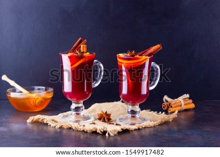 Red mulled wine on burlap. Mulled wine with oranges, honey, cinnamon and cloves on a dark background. Hot wine with honey and spices