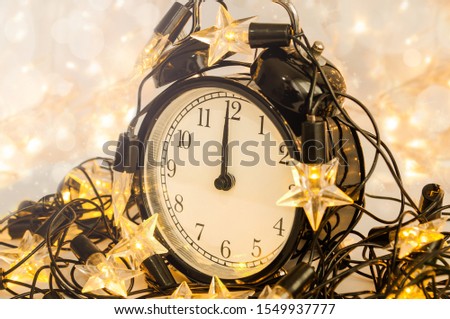New Year alarm clock wrapped into festive star garland. Midnight. Festive Chritmas background.