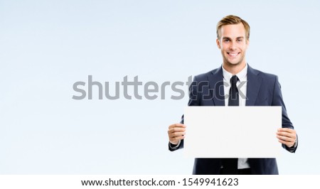 Happy businessman showing blank signboard, isolated against grey background. Empty copy space for some slogan or advertising tsign ext. Success in business concept picture.