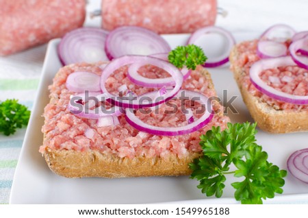 german food mett ground pork, bun and raw meat with onion and parsley, closeup