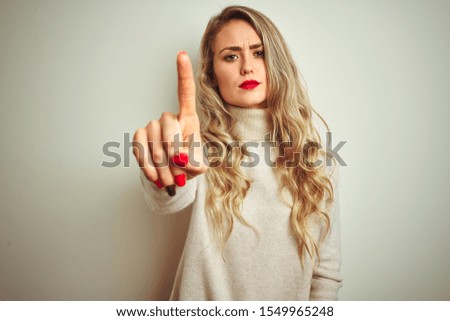 Beautiful woman wearing winter turtleneck sweater over isolated white background Pointing with finger up and angry expression, showing no gesture
