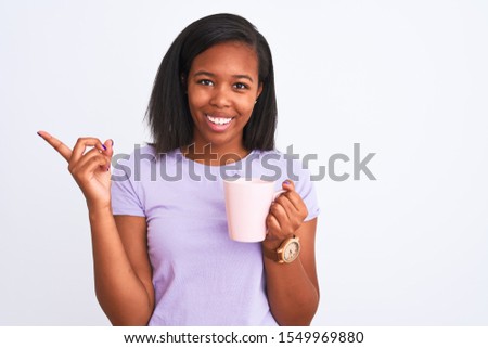 Young african american woman drinking a cup of coffee over isolated background very happy pointing with hand and finger to the side