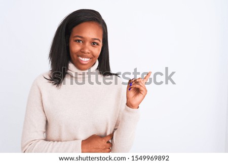Beautiful young african american woman wearing turtleneck sweater over isolated background with a big smile on face, pointing with hand and finger to the side looking at the camera.