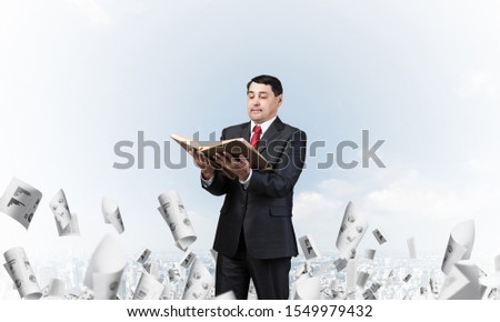 Serious businessman holding open book. Man in business suit standing on cloudy cityscape background with falling paper documents. Business accounting and consulting. Paperwork and bureaucracy