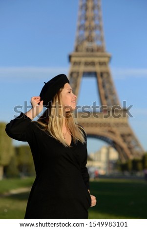 girl in a black dress on a beret in the background of the eiffel tower smiling french blonde joy of recreation of Paris France