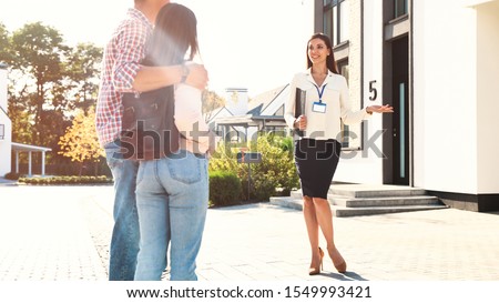 Real estate agent showing house to young couple outdoors