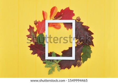 Autumn leaves frame wreath and white wooden frame with place for your text on yellow background. Mockup decor for Thanksgiving day design