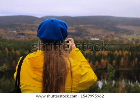 girl taking picture in yellow coat on top of a mountain in sweden