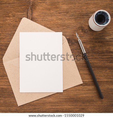 Envelope, ink pen, inkwell on wood table