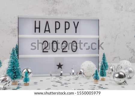 Christmas and New Year concept. White letter lightbox with Happy 2020 words surrounded with christmas decorations