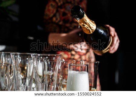 the waiter pours expensive champagne into the glasses during the celebration close-up