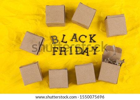 a pile of gift boxes with the words Black Friday lie on a wrinkled yellow cardboard.