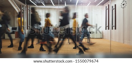 Businesspeople walking at modern office. Group of business employees at coworking center. Motion blur. Concept work process. Wide image Royalty-Free Stock Photo #1550079674