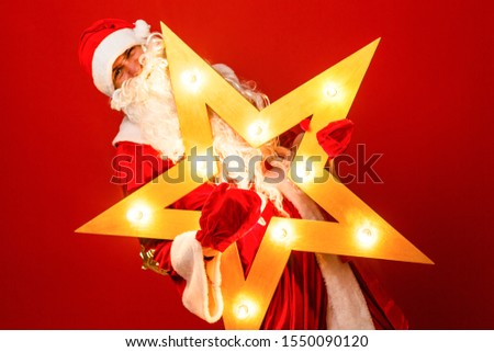 Funny santa claus with big star in Christmas on red background