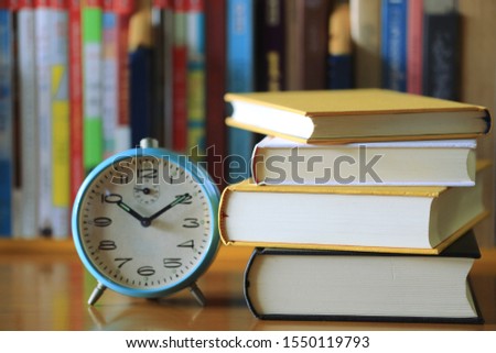Close-up of books stacked on a table and an alarm clock in the library Books arranged in the background selective focus and shallow depth of field
