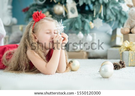 Cute blonde girl 5 years old with christmas star decoration near christmas tree. happy new year 2020 concept. make a wish