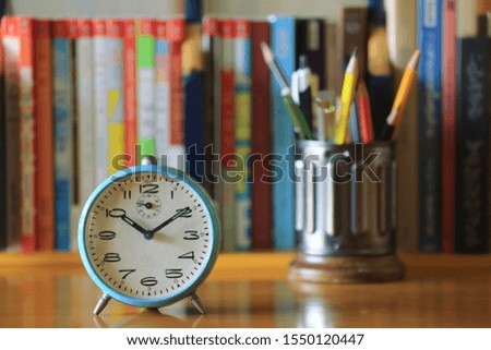 A close up of an ancient alarm clock on the table Many books arranged in the background selective focus and shallow depth of field