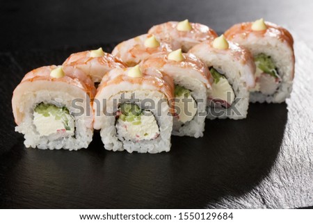 Sushi Rolls with cucumber, shrimp, crab meat and Cream Cheese inside on black slate isolated. Philadelphia roll sushi with shrimp. Sushi menu. Horizontal photo.