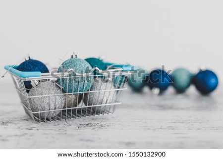festive shopping and decorations conceptual still-life, Christmas baubles in shopping basket with blue and silvery tones shot at shallow depth of field