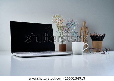 Composition with a modern laptop, a white cup and other vintage things with a delicate bouquet of flowers on a light gray background