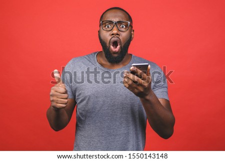 Afro american man using smartphone over isolated red background happy with big smile doing ok sign, thumb up with fingers, excellent sign.