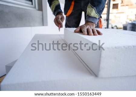 Worker use pen to mark the correct length and dimension of styrofoam during the wall insulation process at the construction site to cut the right size of the board Royalty-Free Stock Photo #1550163449
