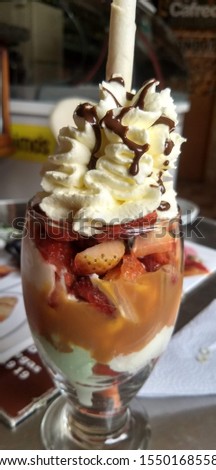 delicious glass of ice cream with a rich cover of whipped cream and chocolate, stuffed with rich strawberries 
