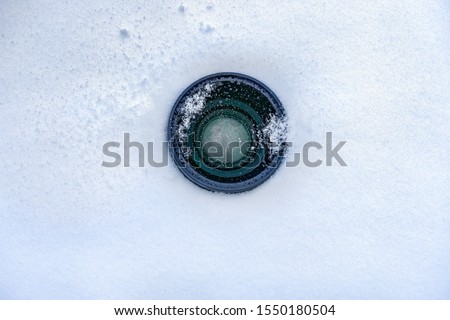 Espionage background. Hidden camera lens in the snow. Black lens of the secret camera is hidden in the snow. Copy space