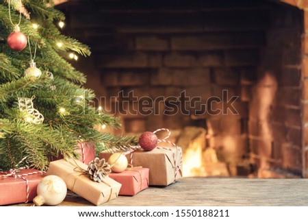 Gifts under the Christmas tree in the room with a fireplace on Christmas eve.