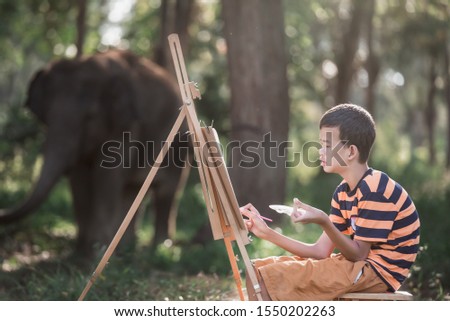Asian boy with Down's syndrome is happily drawing a picture of an elephant in the garden.Drawing, Art Therapy