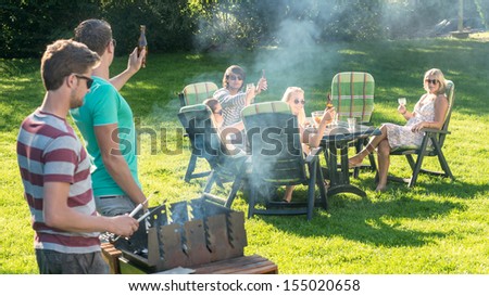 Group of young friends enjoying barbecue in a garden on a sunny afternoon Royalty-Free Stock Photo #155020658