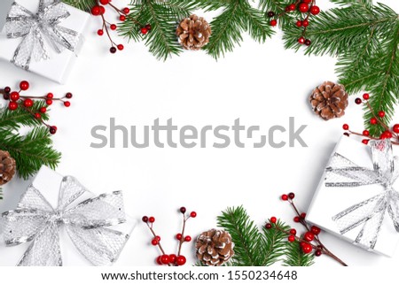 Christmas tree branch with snow , pine cones, red berries and gift boxes on white background with copy space