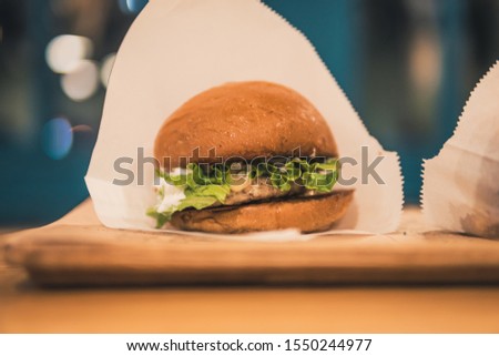 chicken burger on a wooden plate in a cafe