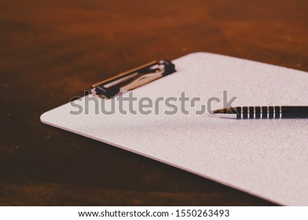 Top view of beautiful vintage silver textured stylish clipboard with modern ballpoint pen on wooden table background. 