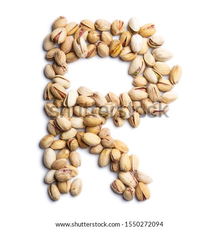 The letter "R" of the English alphabet from a unpeeled  pistachios on a white isolated background.  Unpeeled  pistachios nuts pattern.  healthy food concept. Letters for composing texts