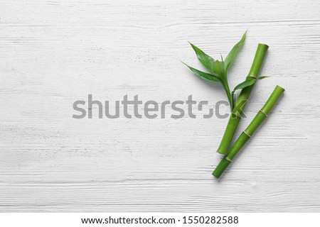 Green bamboo stems on white wooden background, top view. Space for text Royalty-Free Stock Photo #1550282588