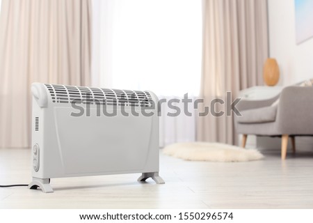 Modern electric heater on floor at home. Space for text Royalty-Free Stock Photo #1550296574