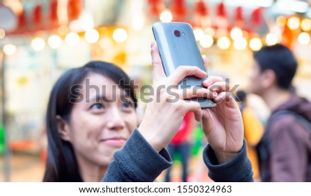 Asian girl making pictures of big city street lights at night.