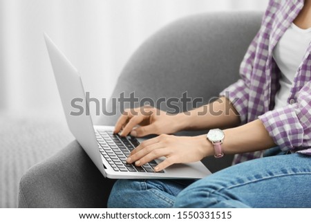 Young woman using laptop at home, closeup